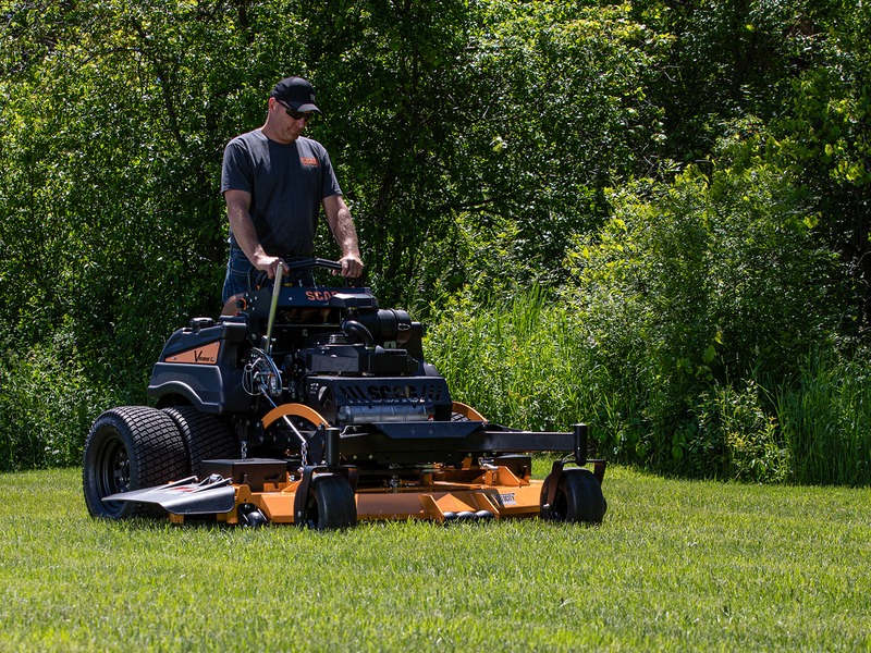 Operator riding a commercial stand-on mower across a green lawn in Kansas City